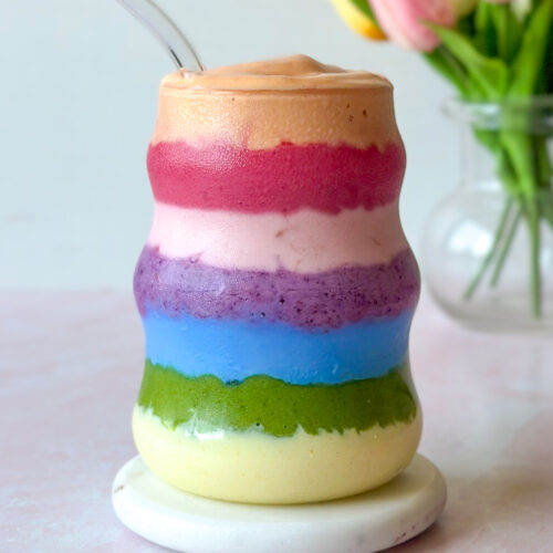 Side view of layered rainbow smoothie revealing vibrant natural color bands