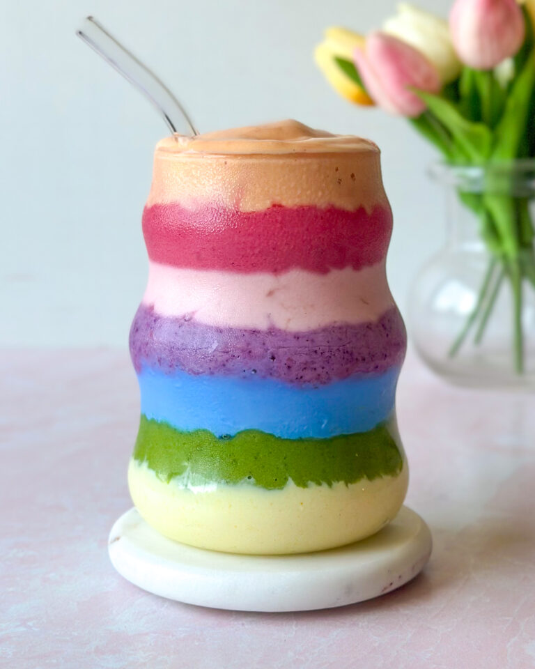 Side view of layered rainbow smoothie revealing vibrant natural color bands