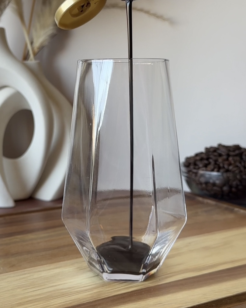 pouring dark chocolate sauce into a glass for tiramisu cold brew