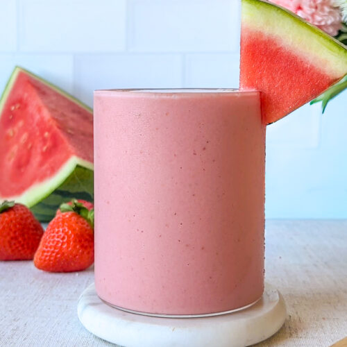 hero image of a finished healthy hydrating strawberry watermelon smoothie, condensation on the glass and a watermelon wedge