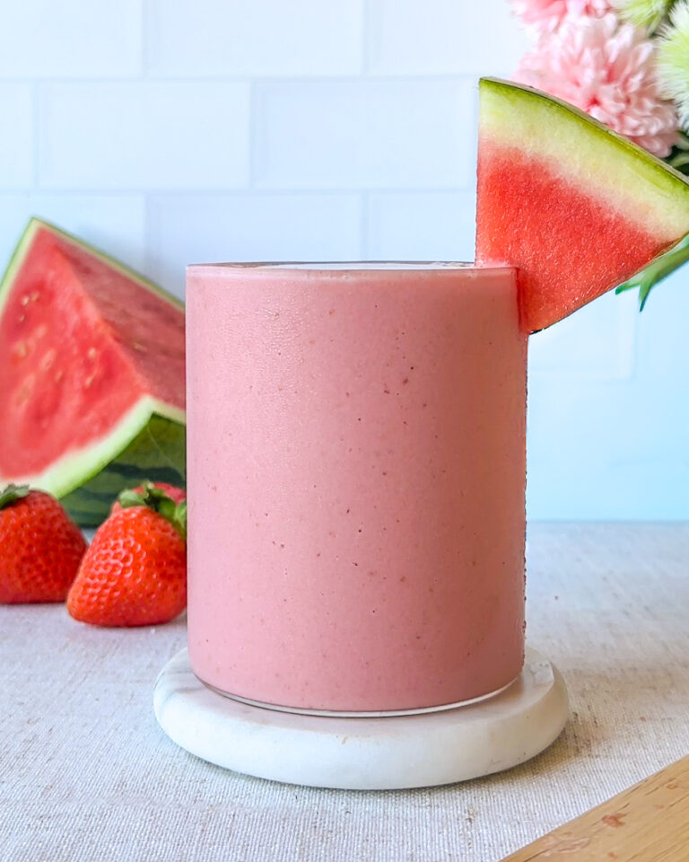 hero image of a finished healthy hydrating strawberry watermelon smoothie, condensation on the glass and a watermelon wedge