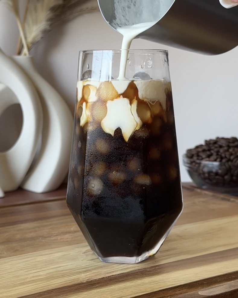 pouring mascarpone colf foam onto of dark chocolate cold brew coffee for tiramisu cold brew iced coffee