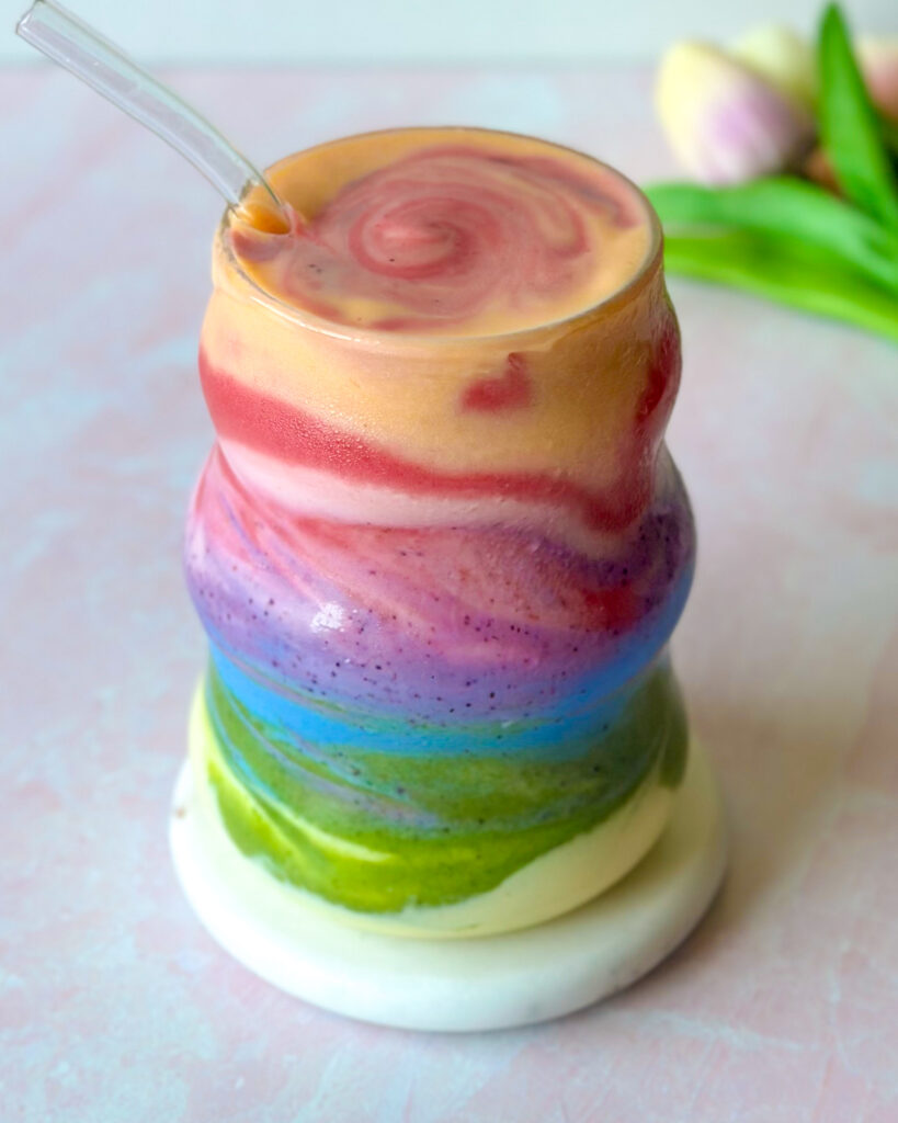 overhead view of layered rainbow smoothie made with natural ingredients in a clear glass