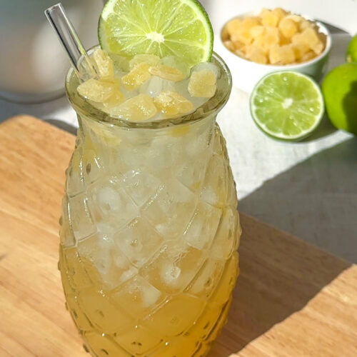 pineapple rum spritz cocktail served over ice and garnished with with fresh lime wheel and dried pineapple cubes