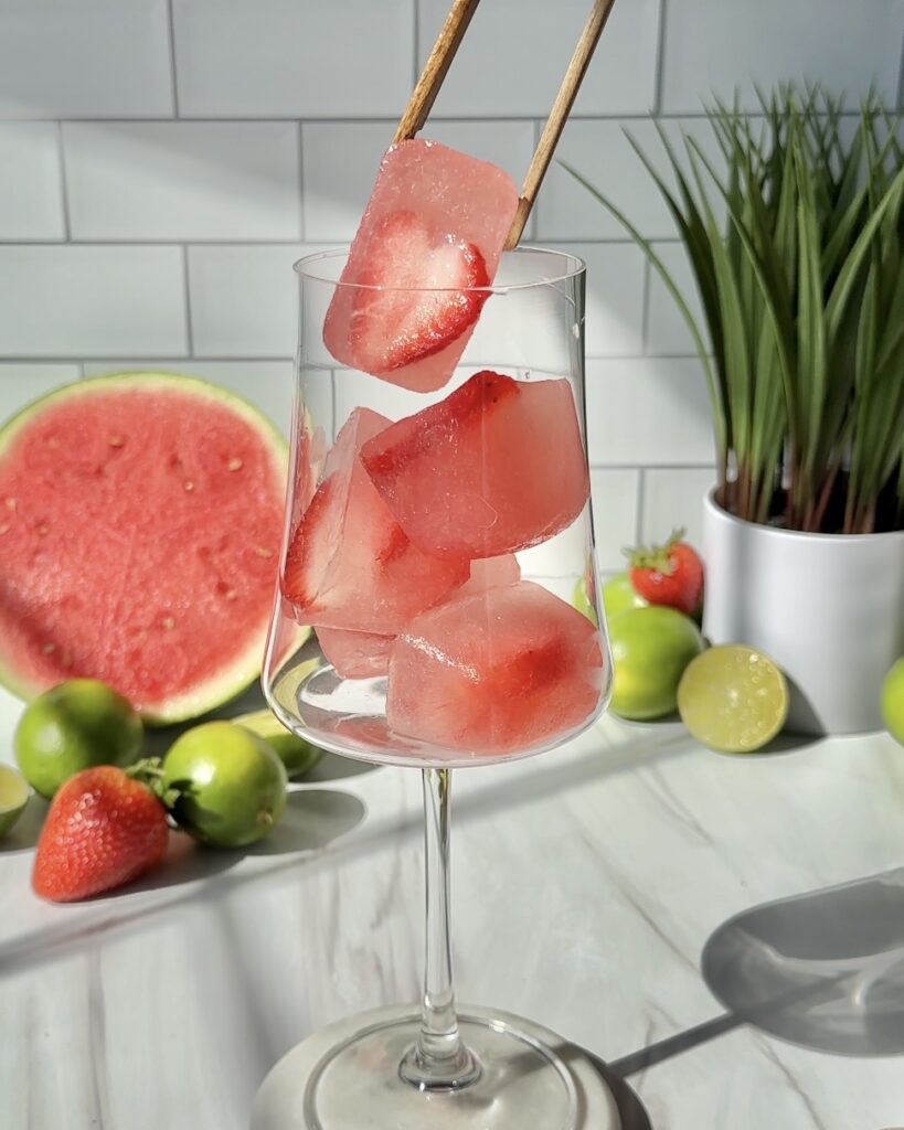 placing watermelon strawberry ice cubes into glass to make watermelon mocktail