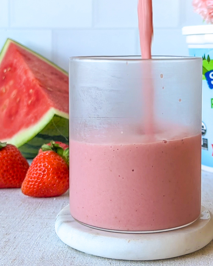 pouring strawberry watermelon smoothie into a chilled glass