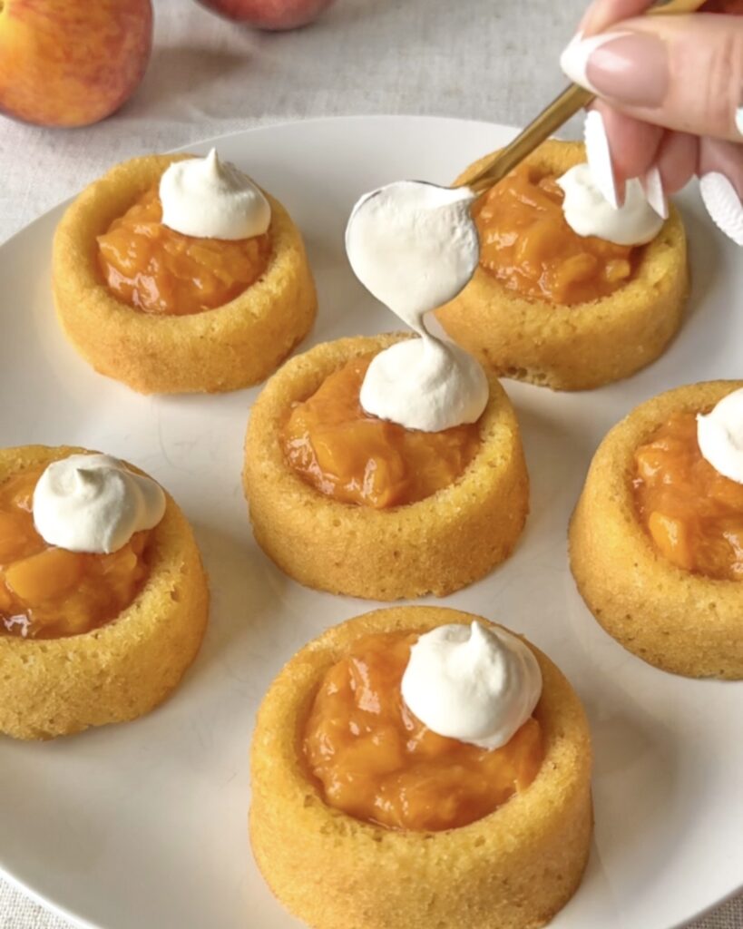 Adding a dollop of whipped topping to homemade peach tarts