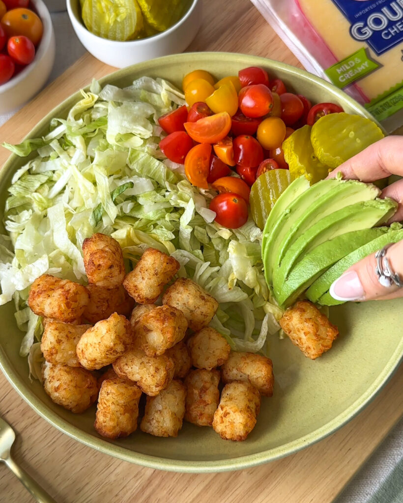 Adding fresh avocado to a homemade burger bowl before serving