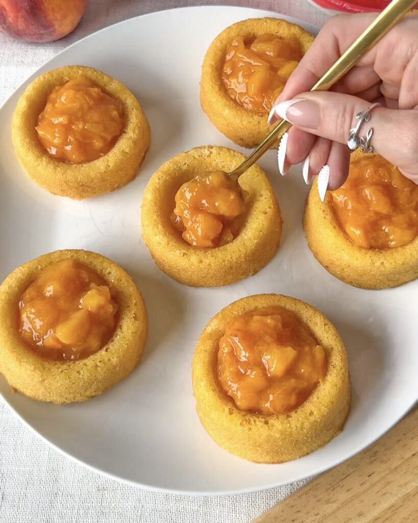 Spooning warm peach filling into crisp mini tart shells before adding the topping.