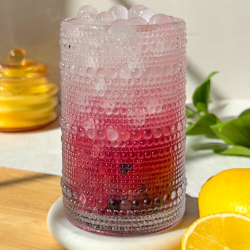 Blueberry hydration drink made with coconut water, fresh blueberries, lemon juice, honey, and Celtic sea salt served over spherical ice cubes.
