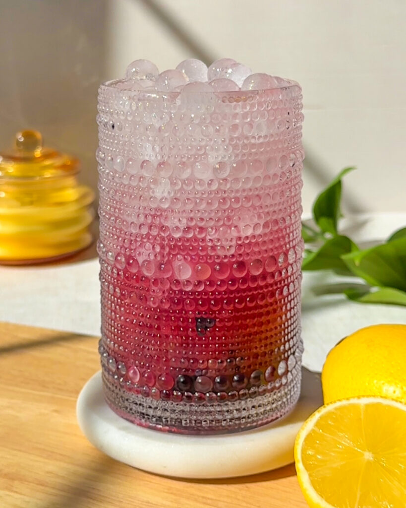 Blueberry hydration drink made with coconut water, fresh blueberries, lemon juice, honey, and Celtic sea salt served over spherical ice cubes.