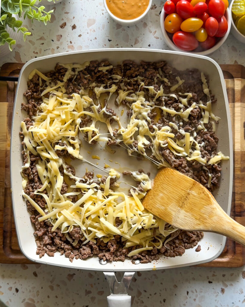 Cheesy ground beef cooking in a skillet for an easy cheeseburger bowl recipe