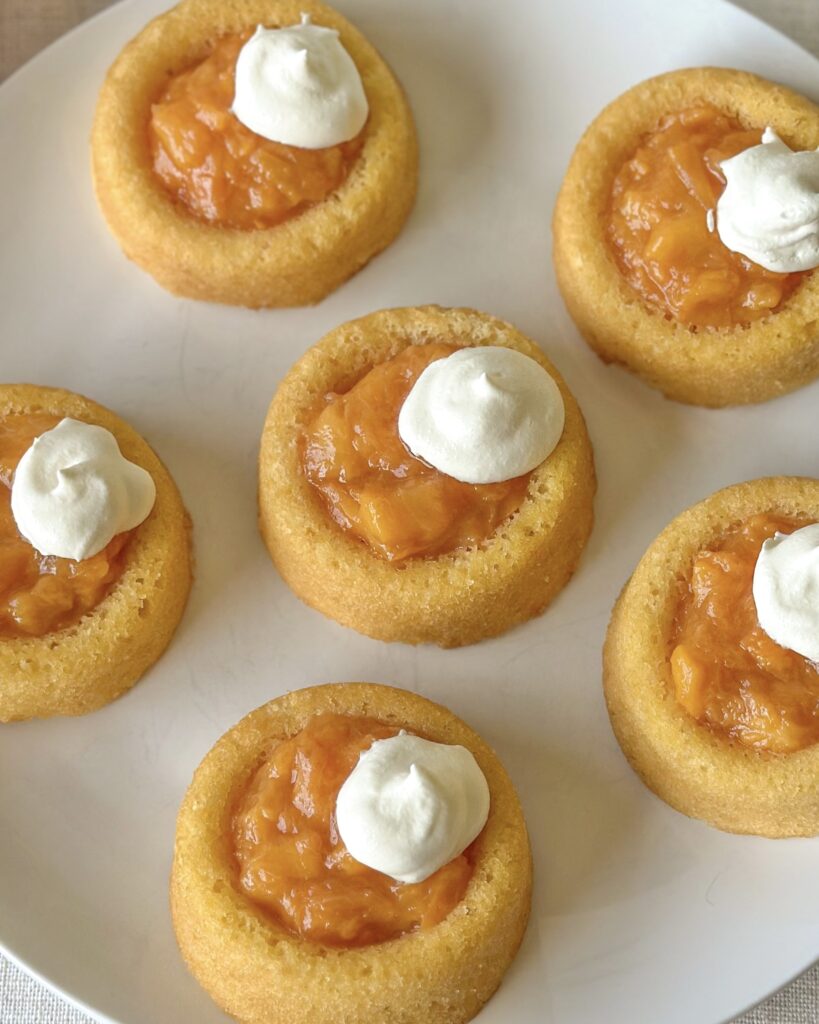 Close-up of easy peach tarts with juicy peach filling and fluffy whipped topping.