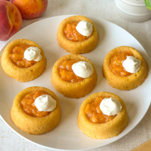 Finished easy peach tarts with fresh peach filling and whipped topping served with ripe peaches.
