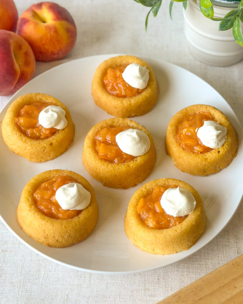 Finished easy peach tarts with fresh peach filling and whipped topping served with ripe peaches.