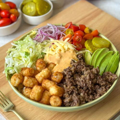 Front view of a loaded burger bowl with crispy tater tots, cheeseburger toppings, and creamy sauce
