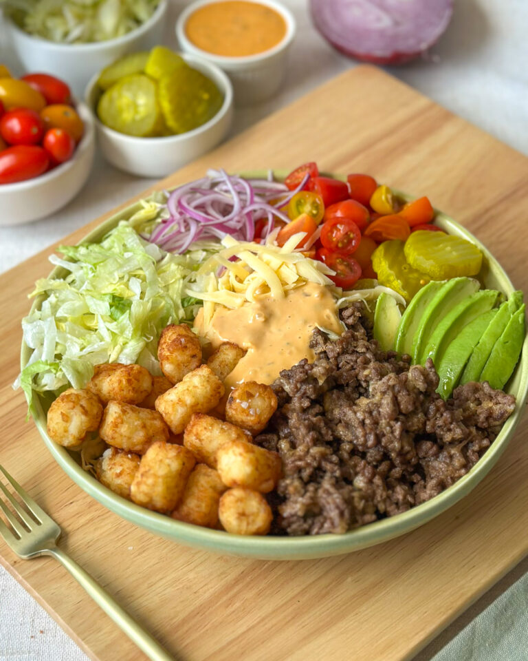 Front view of a loaded burger bowl with crispy tater tots, cheeseburger toppings, and creamy sauce
