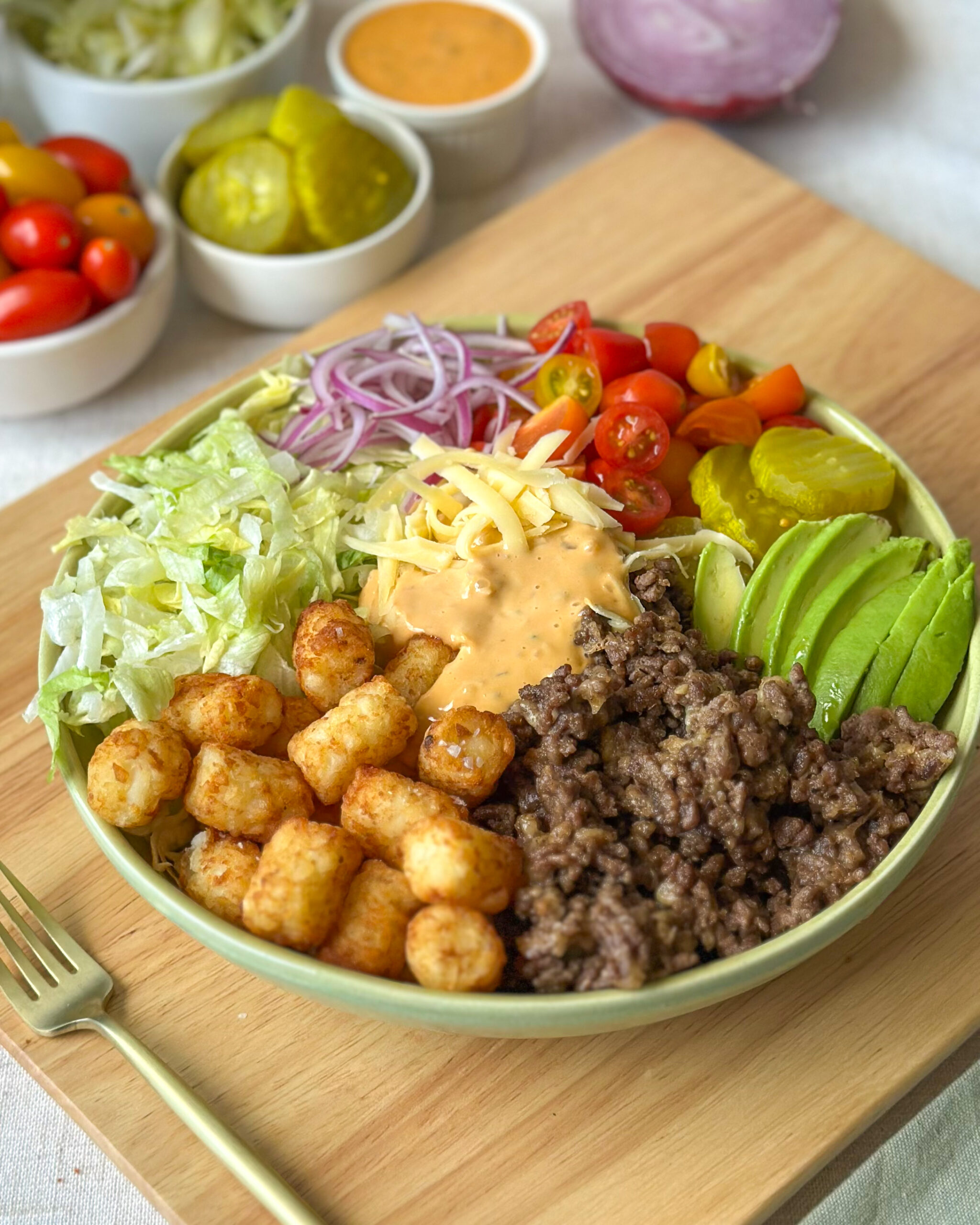 Front view of a loaded burger bowl with crispy tater tots, cheeseburger toppings, and creamy sauce