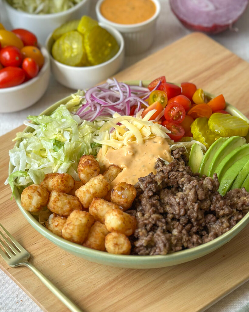 Front view of a loaded burger bowl with crispy tater tots, cheeseburger toppings, and creamy sauce