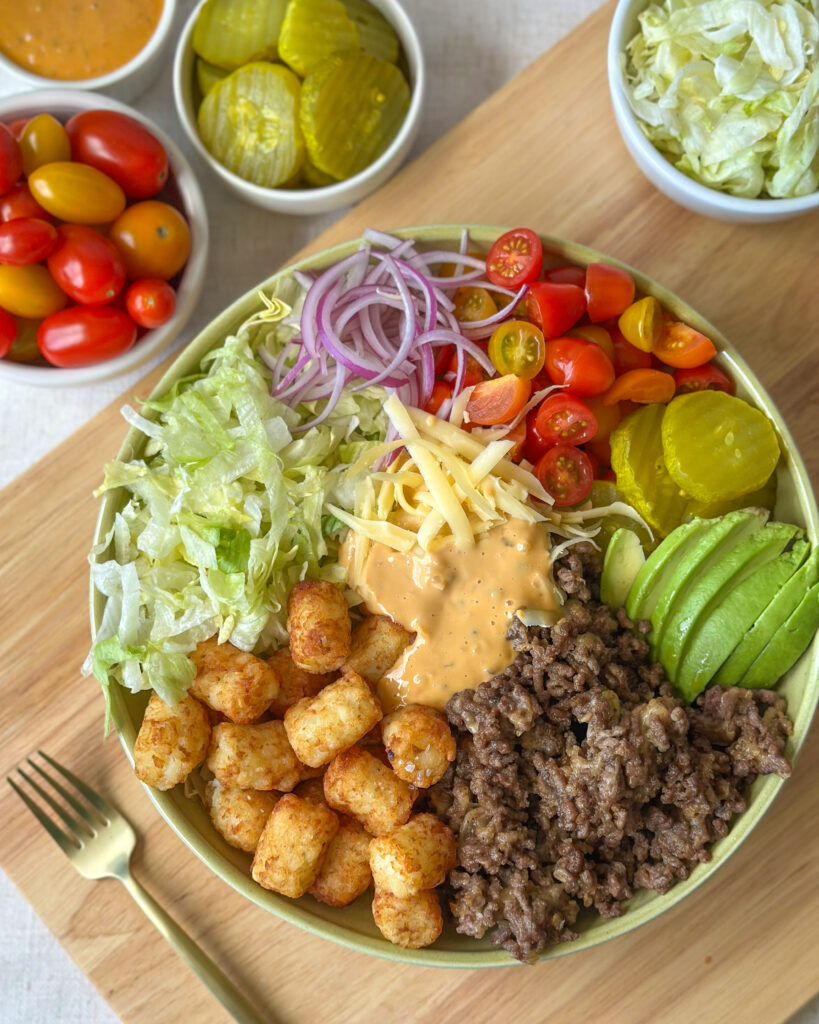 Overhead view of a homemade burger bowl surrounded by fresh toppings and ingredients