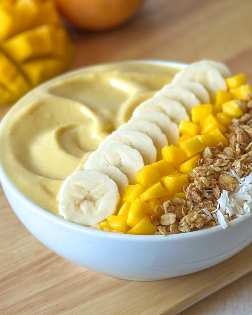 Close-up front view showing the thick creamy texture and toppings of a mango smoothie bowl