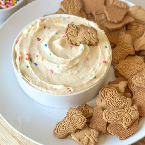 Homemade Dunkaroo dip served with animal crackers on a plate.