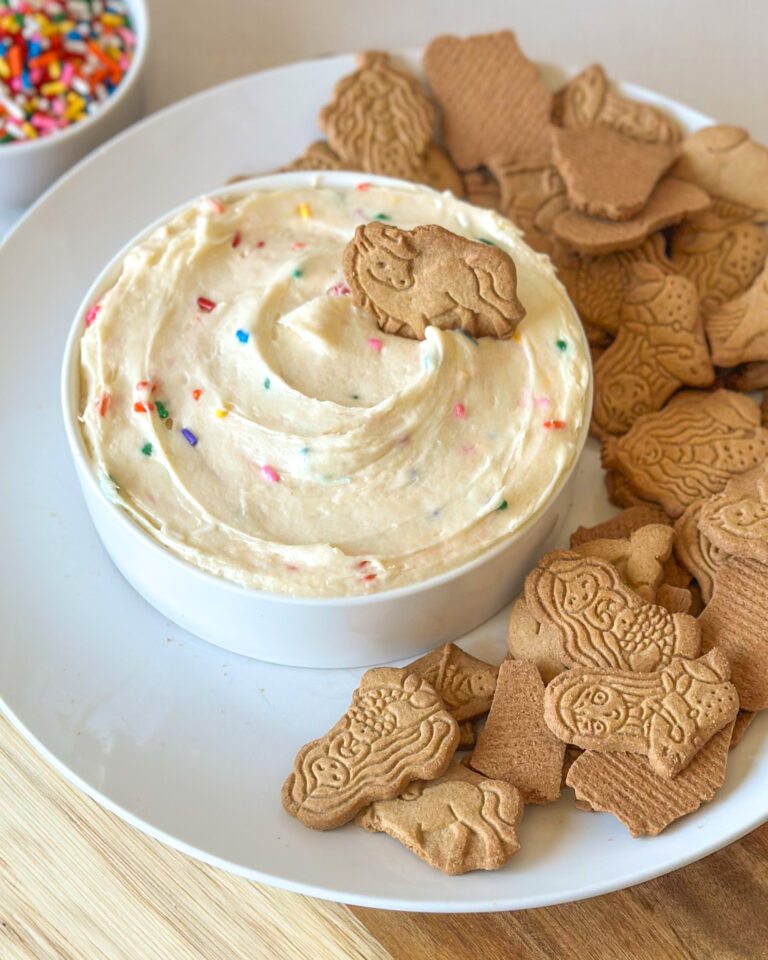 Homemade Dunkaroo dip served with animal crackers on a plate.