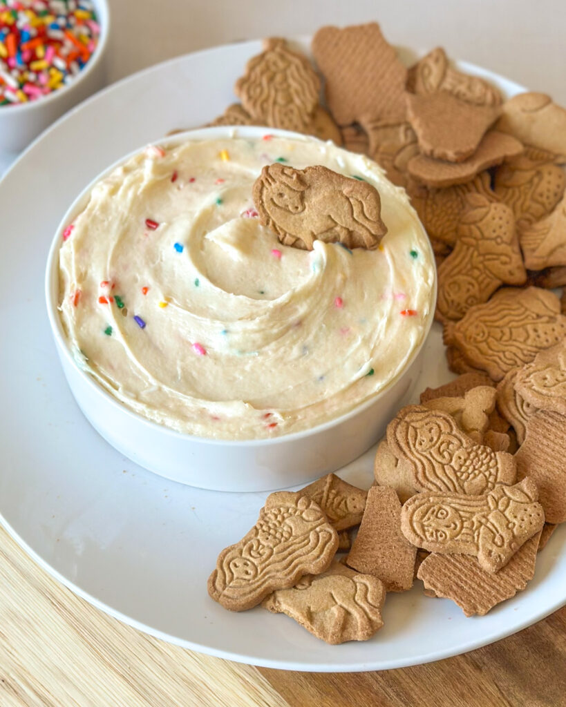 Homemade Dunkaroo dip served with animal crackers on a plate.