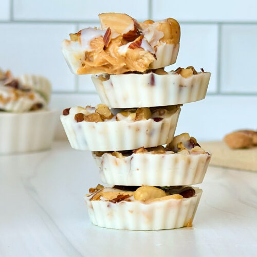 Stack of white chocolate peanut butter cups with the top cup bitten into showing the creamy peanut butter center