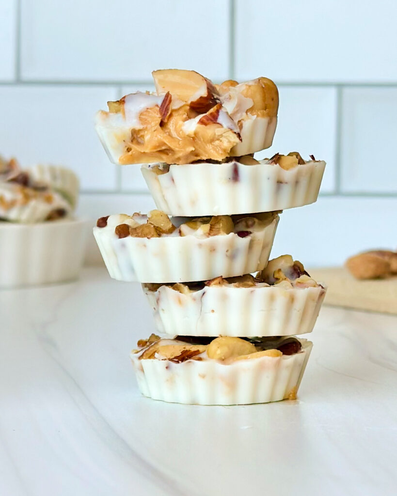 Stack of white chocolate peanut butter cups with the top cup bitten into showing the creamy peanut butter center