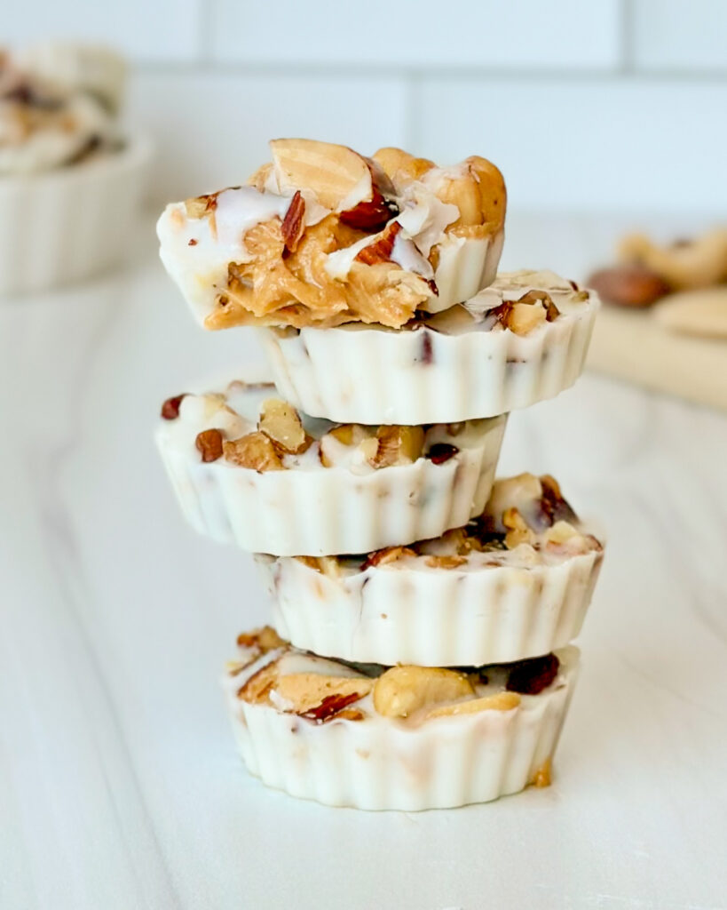 Stack of white chocolate peanut butter cups with the top cup bitten into showing the creamy peanut butter center