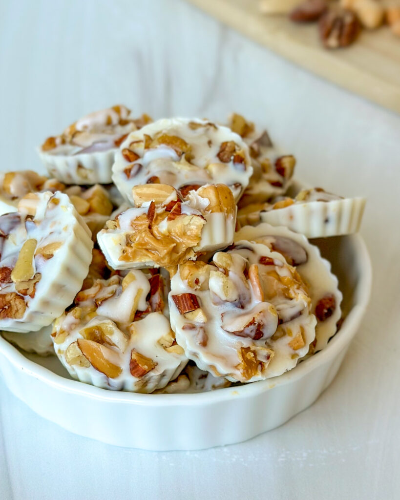 Bowl of white chocolate peanut butter cups with one cup bitten into to reveal the creamy peanut butter center