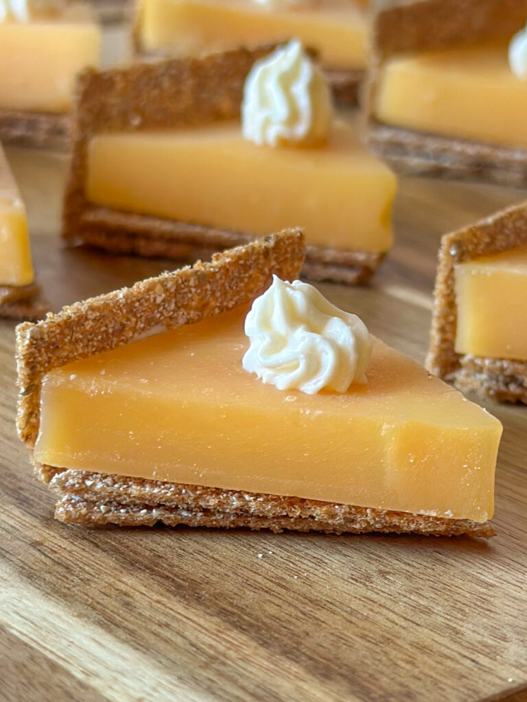 Close-up of a pumpkin pie cheese and cracker bite with more bites blurred in the background