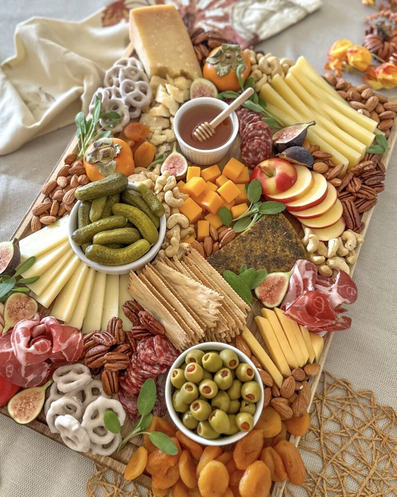 Slightly angled overhead view of a fall cheese and charcuterie board filled with seasonal fruit, cheeses, cured meats, nuts, and crackers
