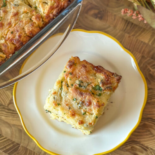 Homemade Cheddar Bay swim Biscuit served on a small plate beside a baking dish filled with golden biscuits