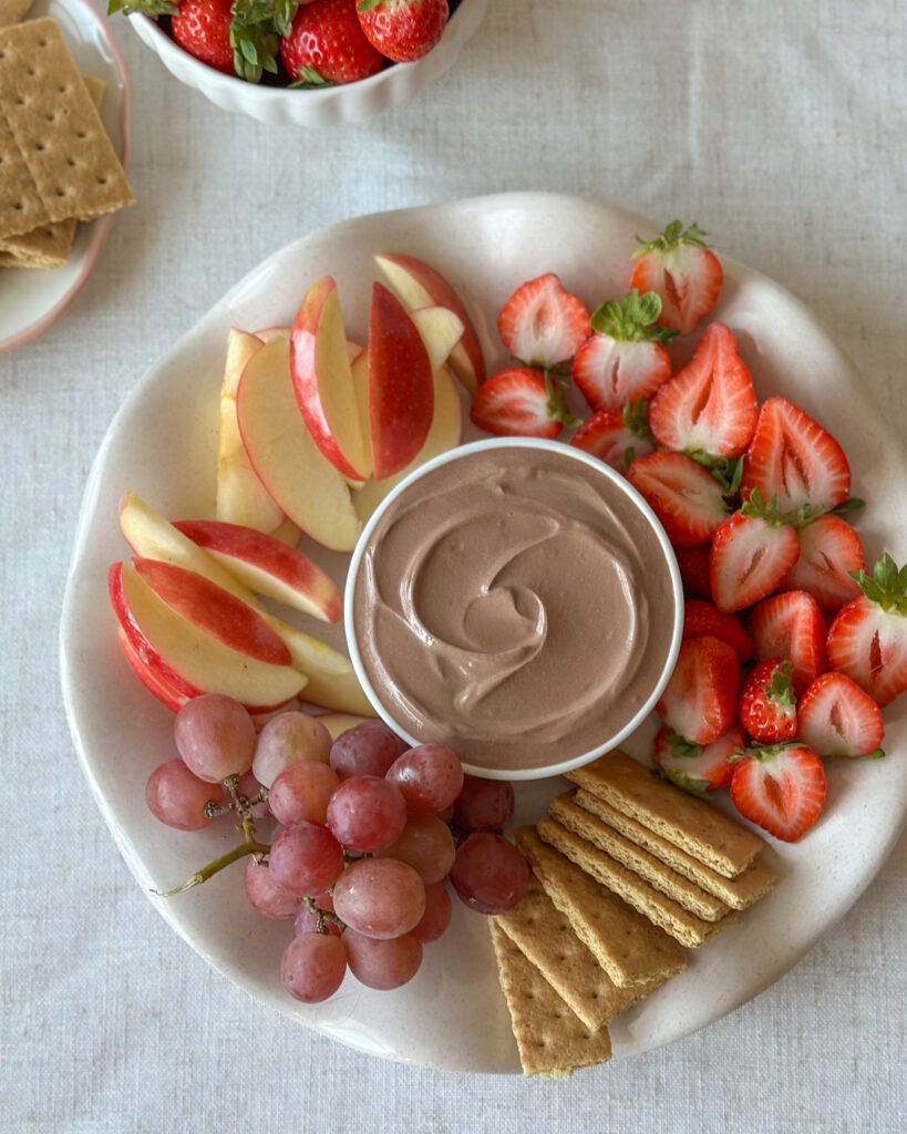 Overhead view of high-protein chocolate dip surrounded by fresh fruit and graham crackers