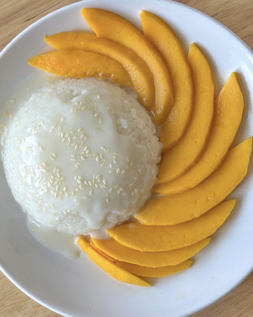 Overhead close-up of mango sticky rice with fresh mango slices spiraled around a beautiful dome of sticky rice.
