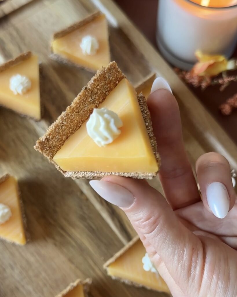 Overhead view of a hand holding a pumpkin pie cheese and cracker bite