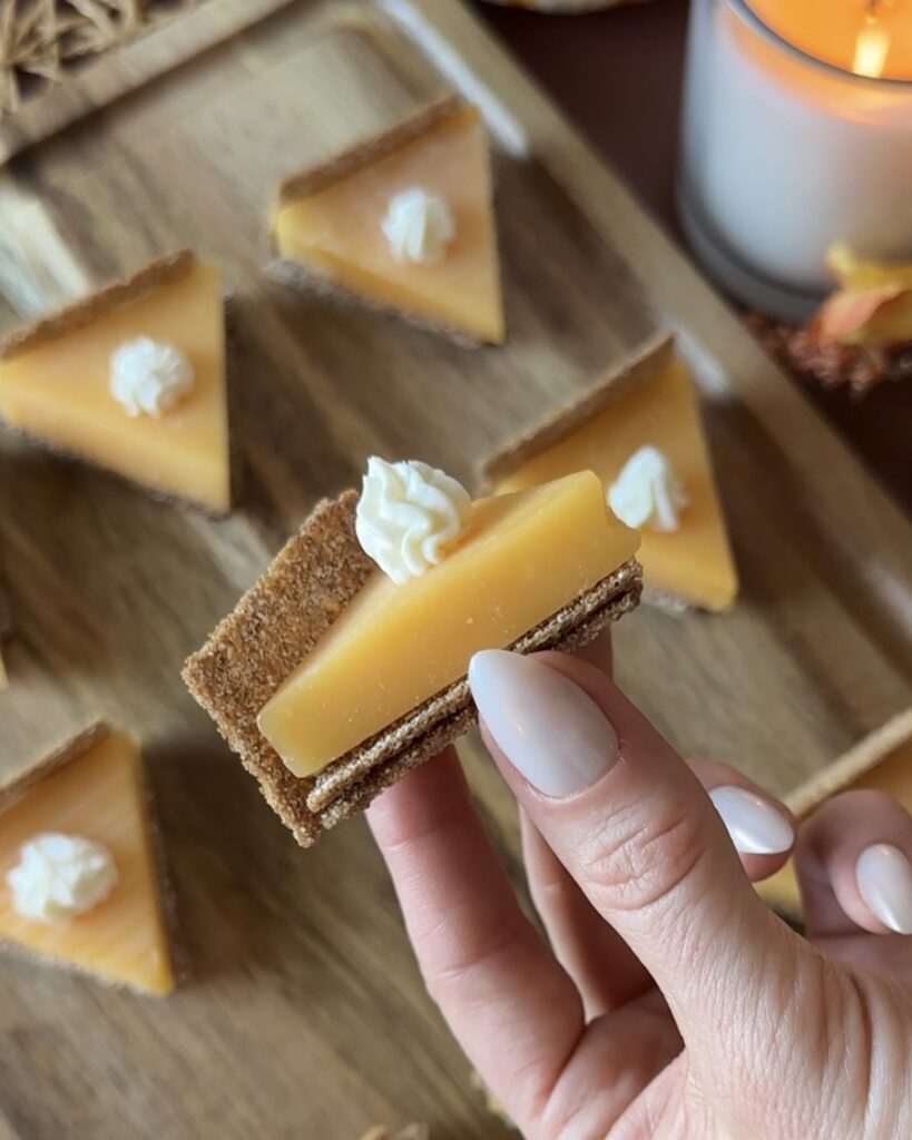 Hand holding a finished pumpkin pie cheese and cracker appetizer