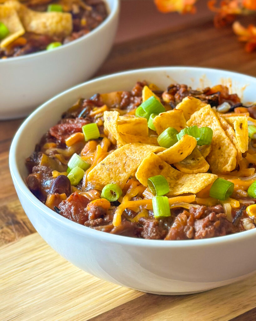 : Close-up of wild rice chili with glistening tomatoes and melted cheese on top