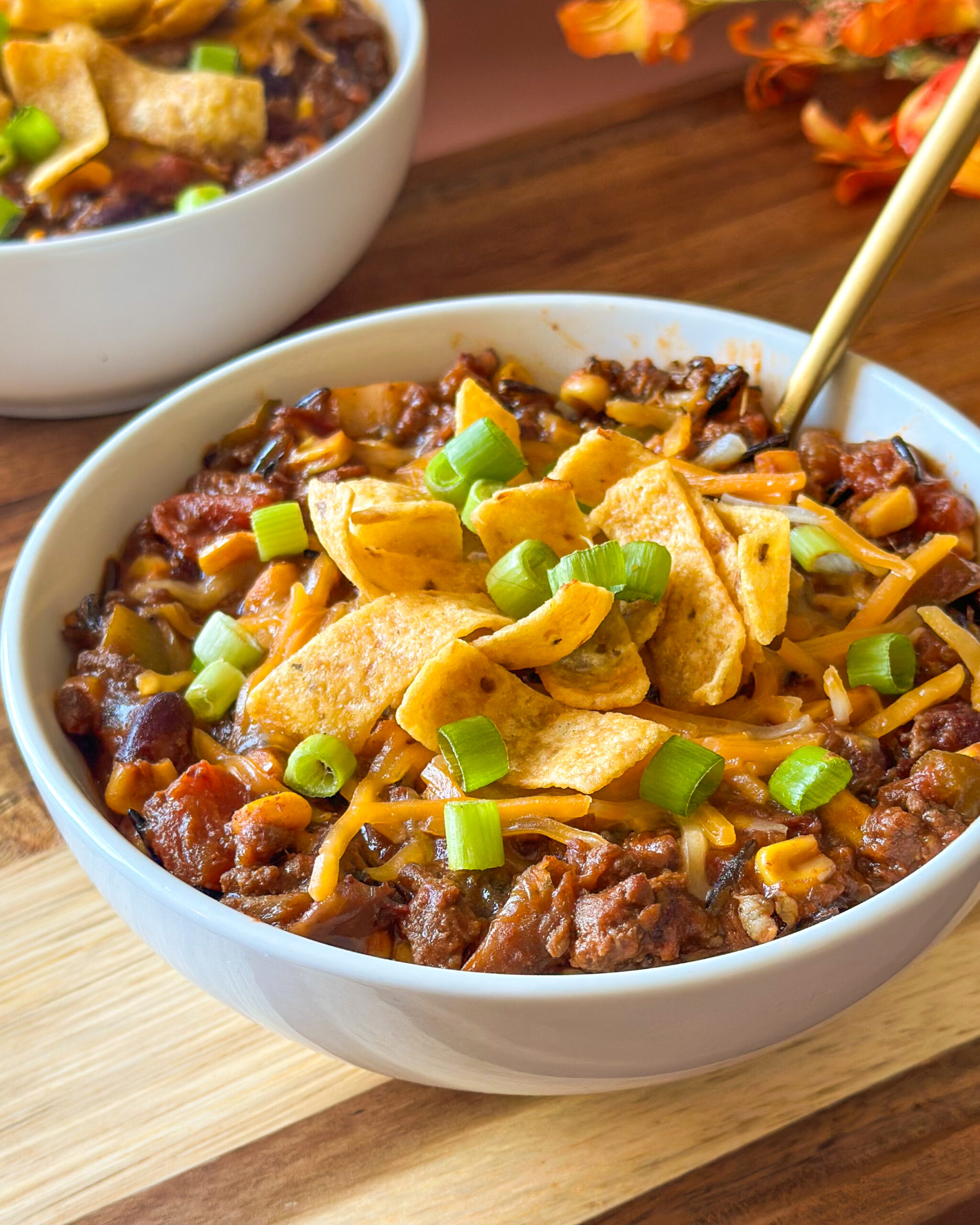 Front view of a bowl of homemade chili with a spoon and another bowl of chili in the background