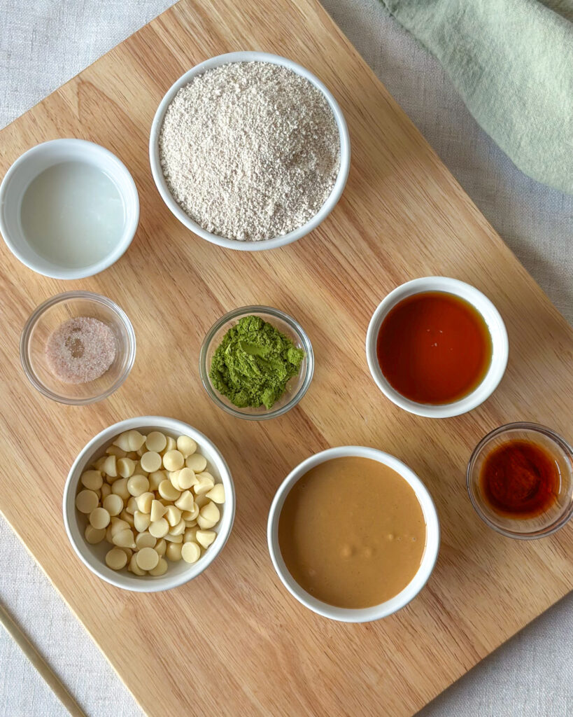 Ingredients for vegan matcha cookie dough including oat flour, matcha powder, maple syrup, cashew butter, vanilla, and sea salt